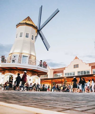 The windmill and main plaza at Acienda Designer Outlet, busy with shoppers